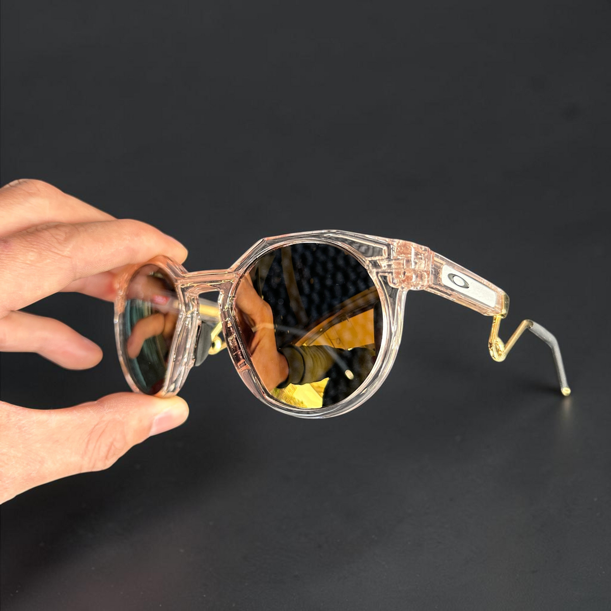 Gafas de sol OakGlasses HSTN Metal con montura transparente y lentes oscuras sostenidas por una mano
