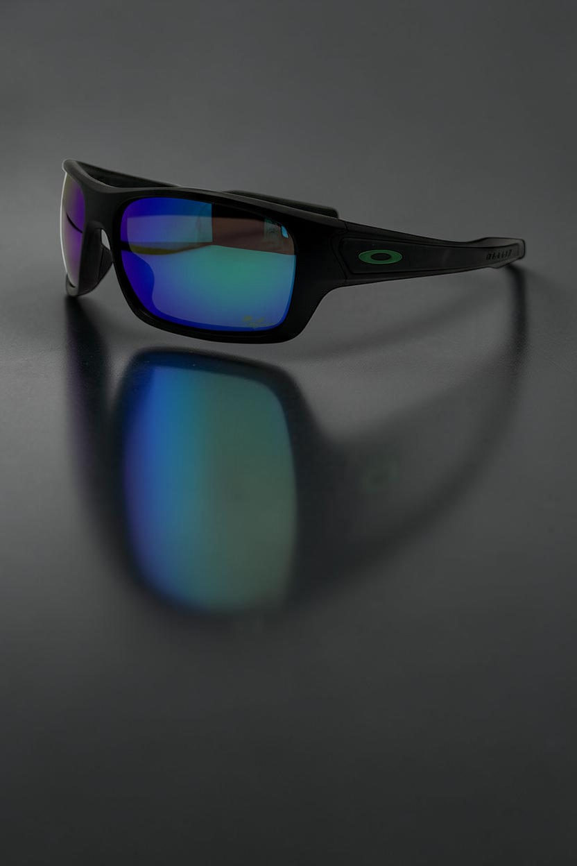 Gafas de sol deportivas OakGlasses Turbine con montura negra mate y lentes reflectantes azules sobre fondo oscuro