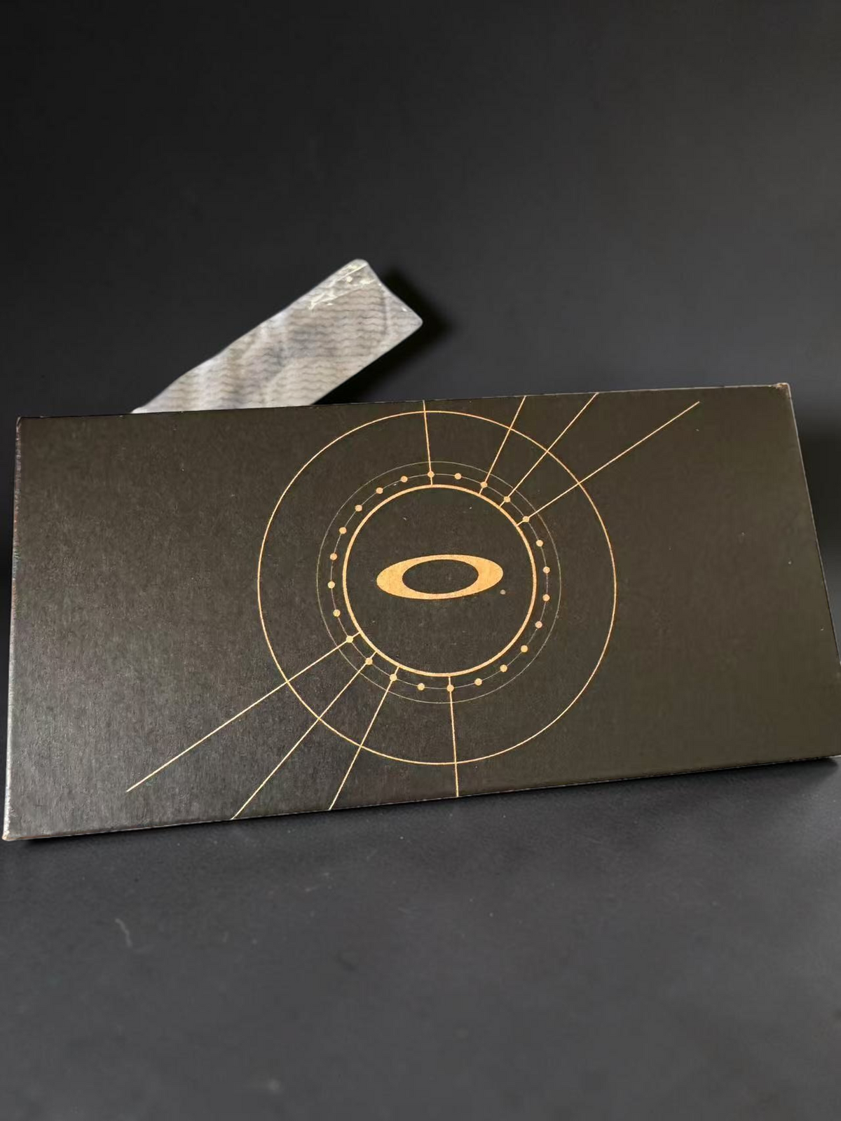 Caja negra de OakGlasses para gafas BXTR Metal con logotipo dorado circular y diseño geométrico en la tapa